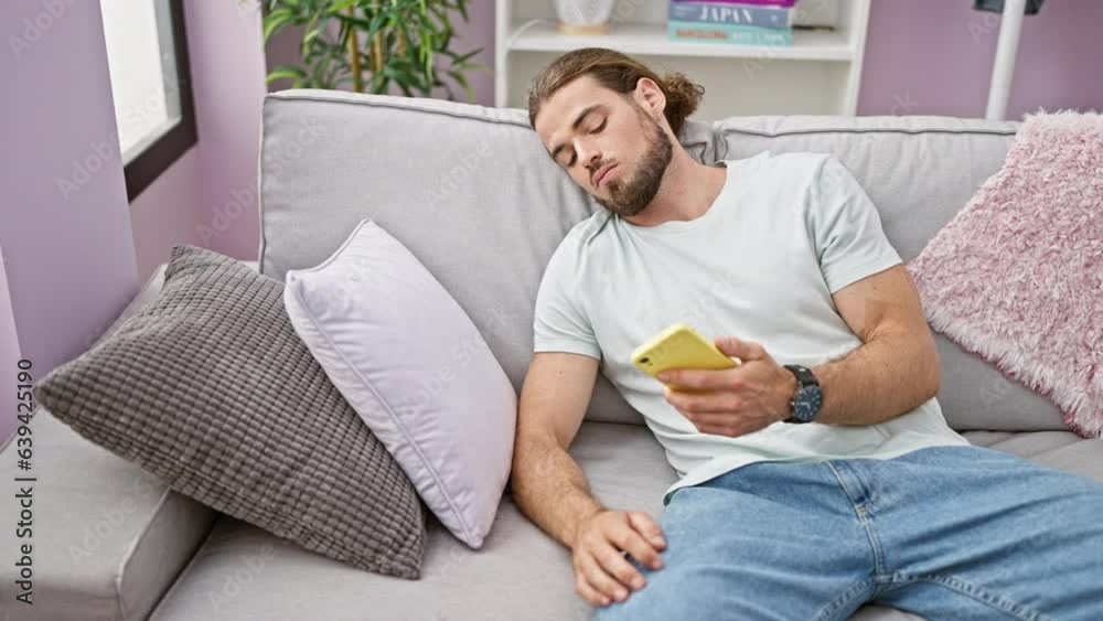 Young hispanic man using smartphone sitting on sofa looking upset at home Young hispanic man using smartphone sitting on sofa looking upset at home