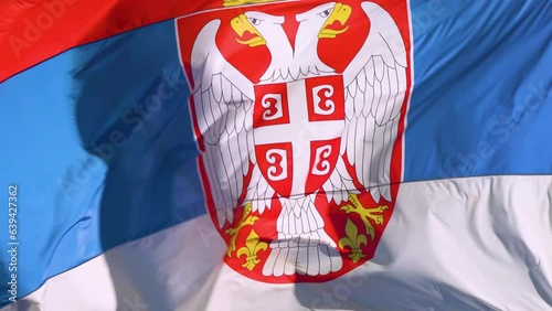 The Serbian flag is flutters (waving) in the wind.