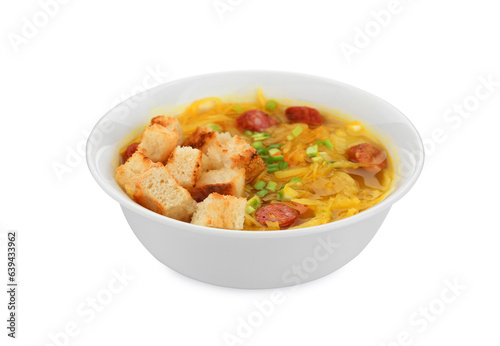 Bowl of delicious sauerkraut soup with smoked sausages, green onion and croutons isolated on white