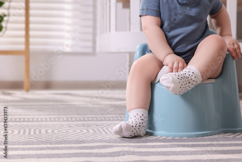 Photo Little child sitting on plastic baby potty indoors, closeup