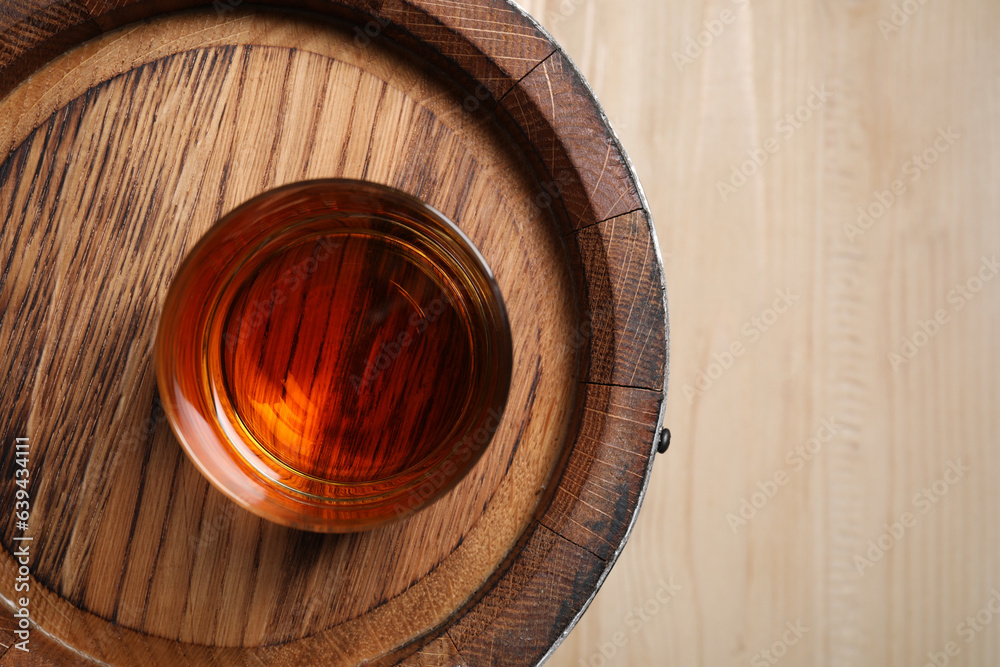 Wooden barrel and glass of tasty whiskey on table, top view. Space for text Wooden barrel and glass of tasty whiskey on table, top view. Space for text