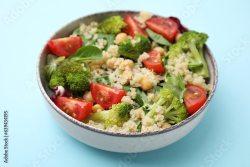 Healthy meal. Tasty salad with quinoa, chickpeas and vegetables on light blue table, closeup