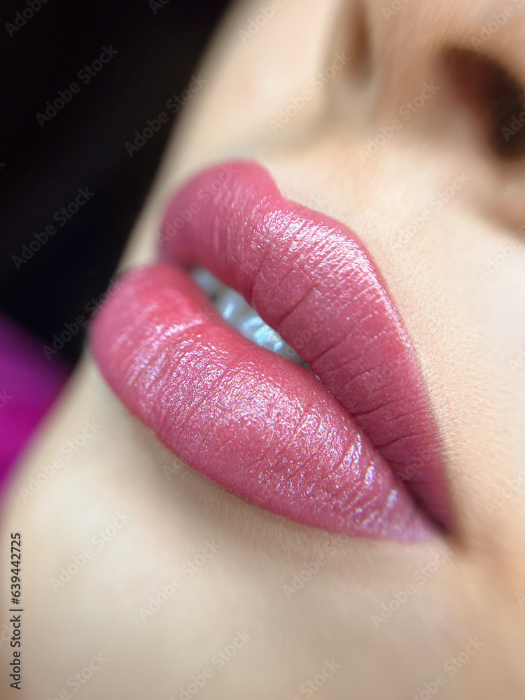 permanent makeup on the lips of a young woman of a delicate peach shade close-up, a girl after a cosmetic procedure with smooth and clean healthy skin. - obrazy, fototapety, plakaty 