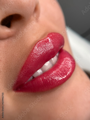 permanent makeup on the lips of a young woman of a delicate peach shade close-up, a girl after a cosmetic procedure with smooth and clean healthy skin.