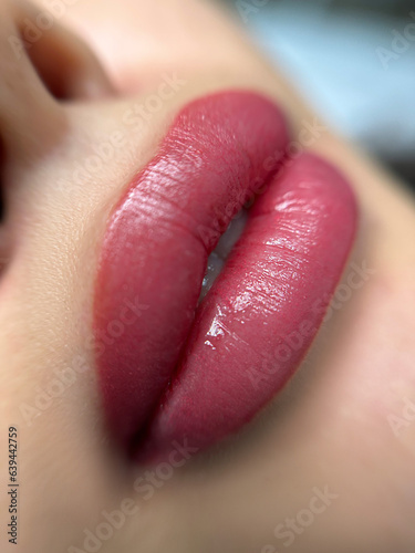 permanent makeup on the lips of a young woman of a delicate peach shade close-up, a girl after a cosmetic procedure with smooth and clean healthy skin.