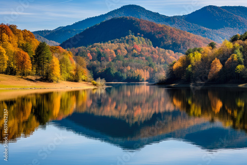 A beautiful autumn landscape. A lake with a mirror-like reflection of the surrounding hills and trees. The hills in the background are covered in dense forests