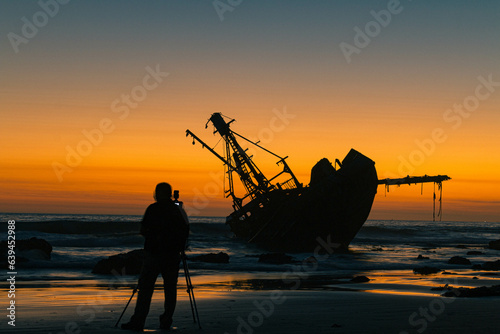 silhouette of a person at the beach and boat
