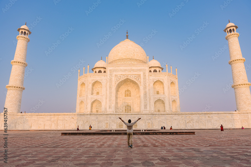 The man with arms around his back standing in front of Taj Mahal indian palace. Islam architecture. 
