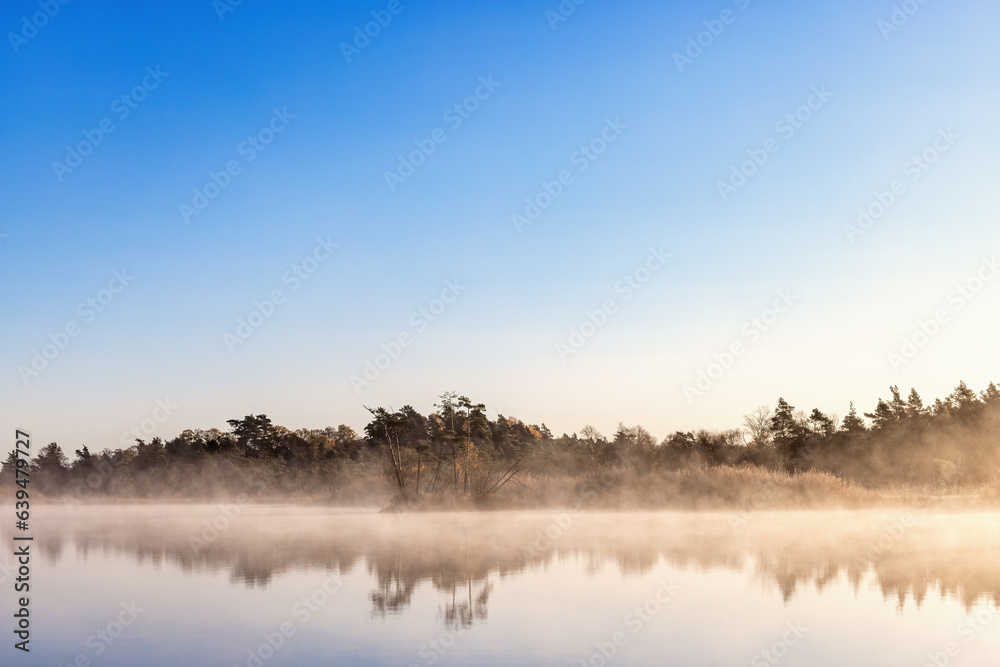 Beautiful autumn morning by a forest lake with fog