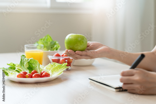 Wellbeing of health with good food control concept. Woman writing the meal note and plan to eat during diet program to loss weight goal for balance nutrition and calories.