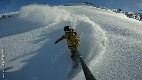 Snowboard freeride skiing in resort, active man 40 years old enjoying fresh snow doing powderterns snowboarding in powder day, filming selfie stick. Adrenaline junkie gets his fill from snowboarding photo