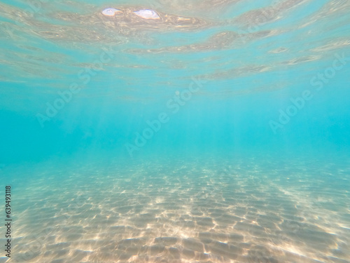 Clean water. Under the water, the rays of the sun and the sandy bottom. natural background