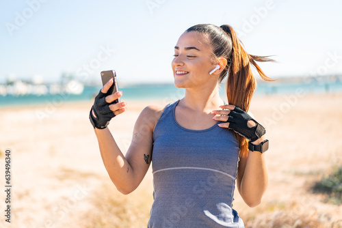 Young pretty sport woman wearing sport wear and listening music with phone