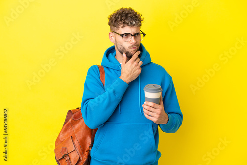 Young student blonde man isolated on yellow background having doubts and thinking