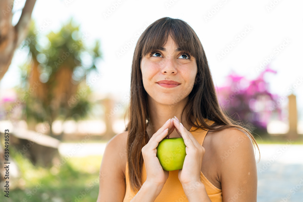 Young woman at outdoors holding an apple Young woman at outdoors holding an apple