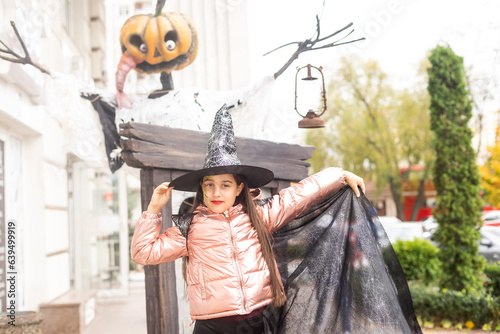 teenage girl in witch hat plays in the park, child plays wizard, costume for halloween concept