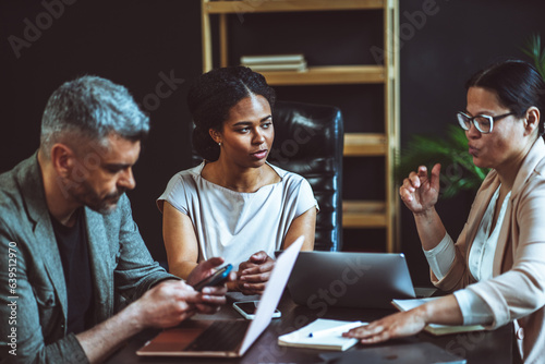 Business meeting where diverse team of businessmen engages in focused discussion about problem-solving. Multi-ethnic team members come together to exchange ideas and brainstorm solutions. High quality