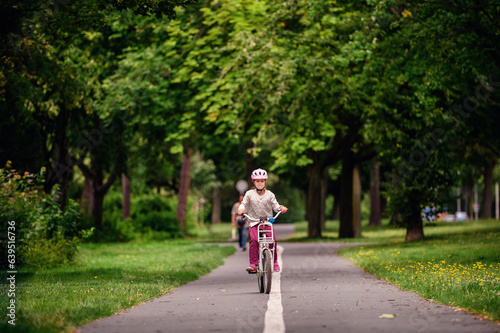 Wallpaper Mural Little schooler girl riding bike in parks. Summer time, wearing helmet. From the back. Torontodigital.ca