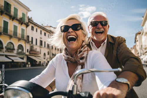 Happy senior couple having fun! Riding motor bike scooter across the town and waving! Retirement adventure life. © Uros