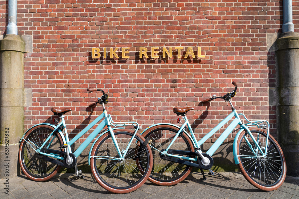 Naklejka premium Bikes for rent near brick wall in Amsterdam, Netherlands