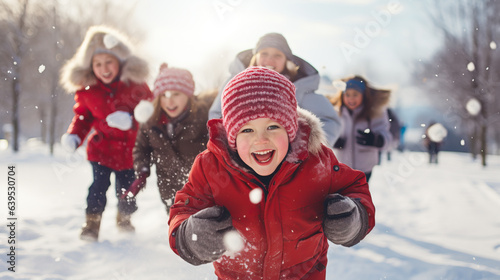 Children playing in the snow during a sunny winters day. Active children, snowball fights and joy in the cold season. Shallow field of view.