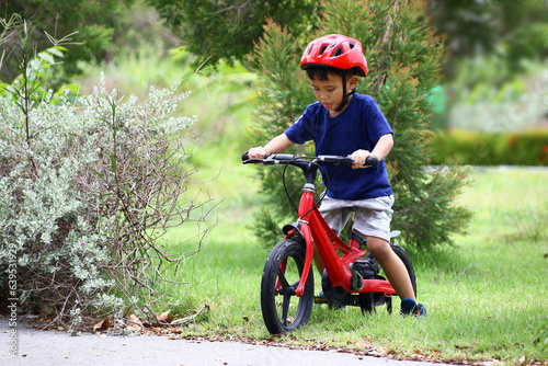 Asian Little boy riding a red bicycle in park