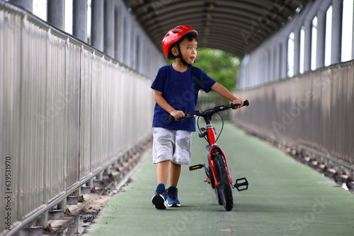 Asian Little boy riding a red bicycle in park