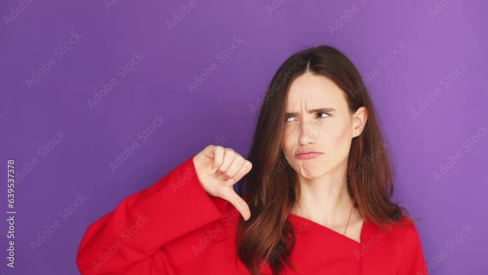 Sad woman show thumb down and next change on thumb up gesture and change emotion to positive, and also bad. Young woman in red sweater making bad-good-bad sign isolated on purple background. Decision. Sad woman show thumb down and next change on thumb up gesture and change emotion to positive, and also bad. Young woman in red sweater making bad-good-bad sign isolated on purple background. Decision.
