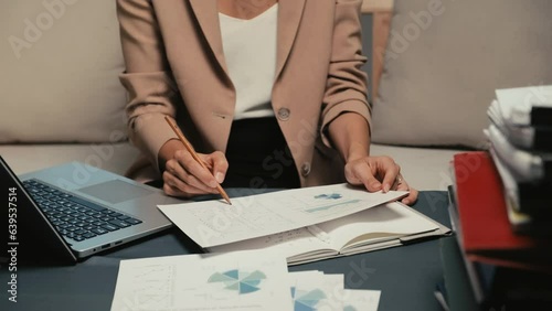 Cropped shot of female business worker revising financial document with chart at officeCropped shot of female business worker revising financial document with chart at officeCropped shot of female bus photo