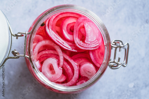 Close up pickled red onions rings in glass jar on a gray background. Fermented vegetarian food concept. Healthy eating