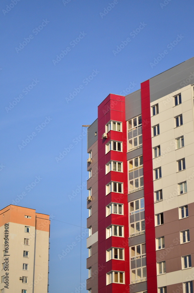 A new multi-colored house against the background of an old high-rise building