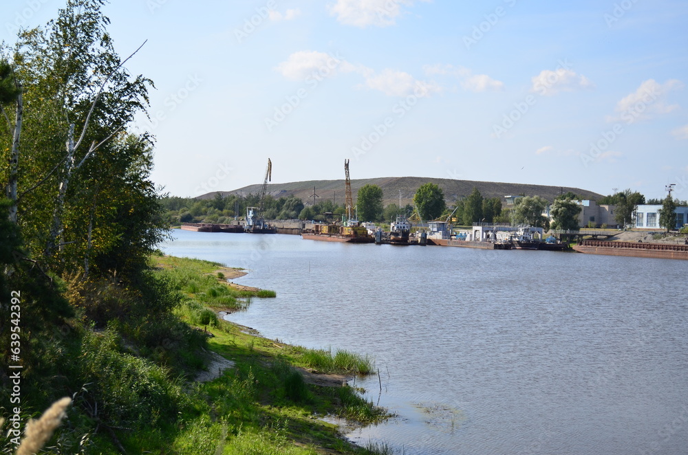 Cargo barges stand on the river near the enterprise