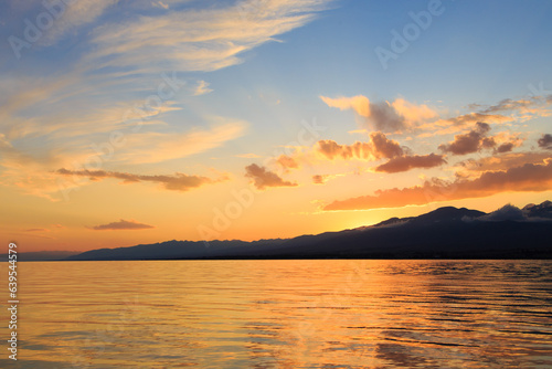 Colorful sunset on the sea. Mountain lake in the rays of the orange sun. Kyrgyzstan  Lake Issyk-Kul.
