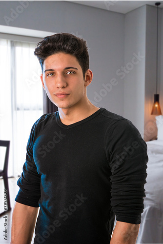 male model standing in his bedroom, looking at camera with a seductive attitude