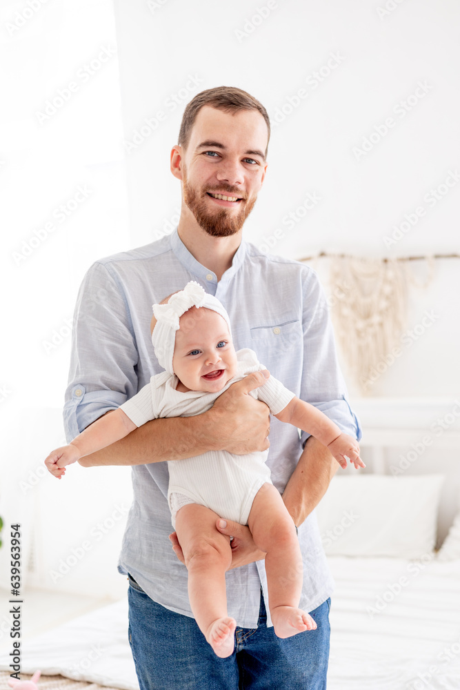Obraz premium a happy dad with a little newborn daughter, the concept of fatherhood, a dad on maternity leave with a baby in his arms, a cute photo of a dad with a daughter
