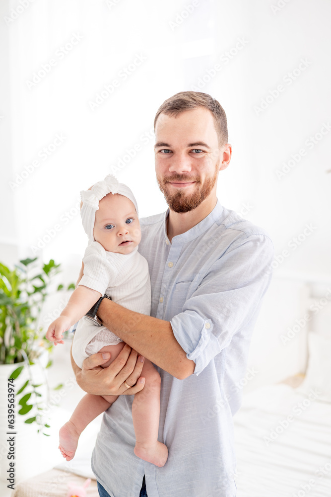 Obraz premium a happy dad with a little newborn daughter, the concept of fatherhood, a dad on maternity leave with a baby in his arms, a cute photo of a dad with a daughter