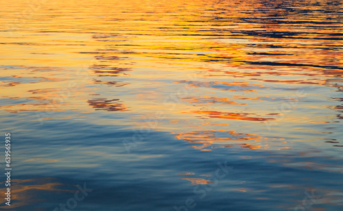 Clear water texture in blue and orange. sky and clouds reflection. Background of the ocean and the sea backlit by the sun. © Alwih