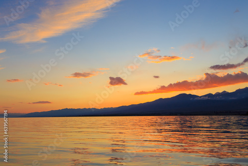 Beautiful cloudy sunset over the sea and mountains. Bright sky in the rays of the orange sun. natural texture