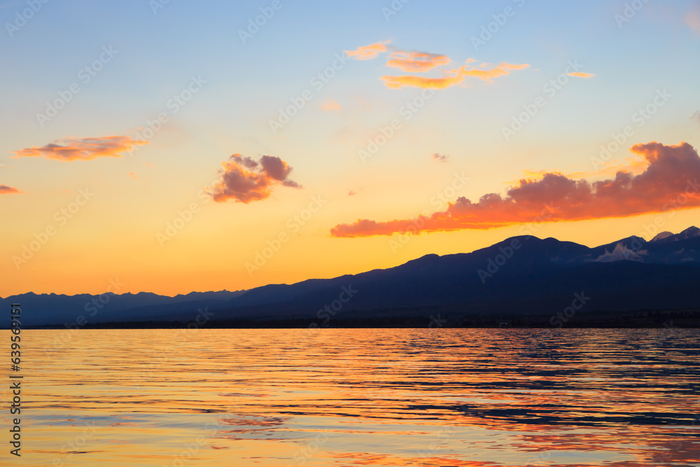 Colorful sunset on the sea. Mountain lake in the rays of the orange sun. Kyrgyzstan, Lake Issyk-Kul. Colorful sunset on the sea. Mountain lake in the rays of the orange sun. Kyrgyzstan, Lake Issyk-Kul.
