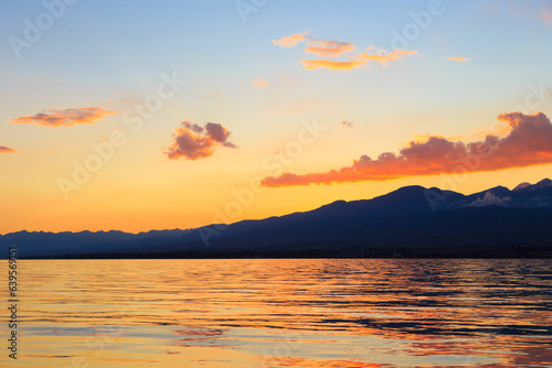 Colorful sunset on the sea. Mountain lake in the rays of the orange sun. Kyrgyzstan, Lake Issyk-Kul. © Alwih