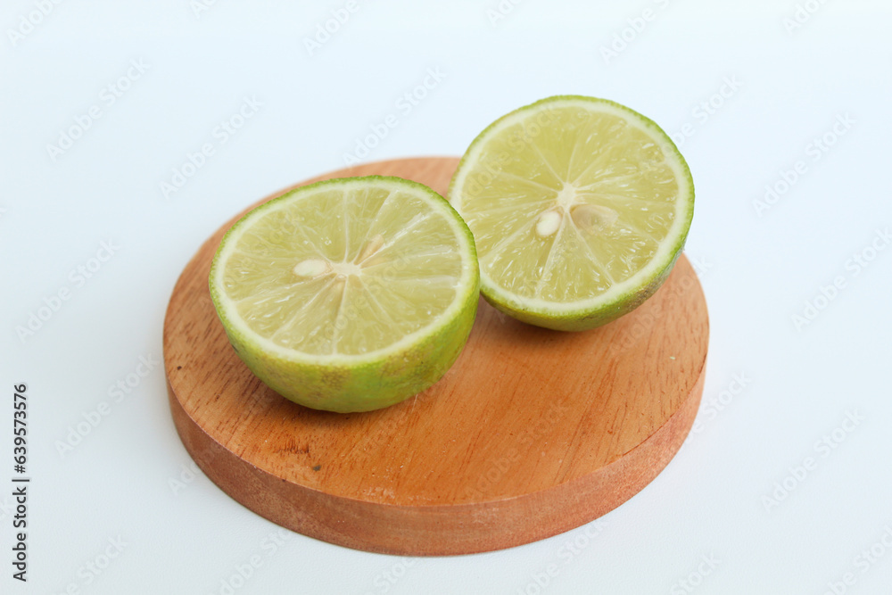 Halves of Green Lime, on wooden base, isolated on white background Halves of Green Lime, on wooden base, isolated on white background
