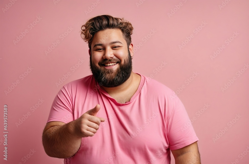 Happy young man with overweight and beard isolated on a pink background, looks into the camera and smiles. Fat guy in a pink shirt Happy young man with overweight and beard isolated on a pink background, looks into the camera and smiles. Fat guy in a pink shirt