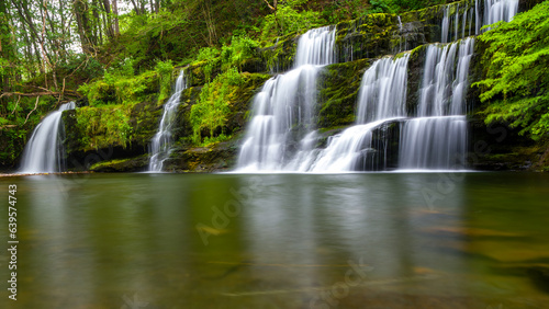 Cascading waterfall in a lush green forest  Sgwd y Pannwr  Wales 
