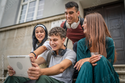 group of students sit in front of school watch video on digital tablet © Miljan Živković