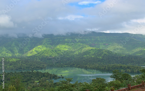Panoramic landscape view of beautiful lush green Sahyadri mountains with windmills visible through clouds on the top at Tapola, Maharashtra, India