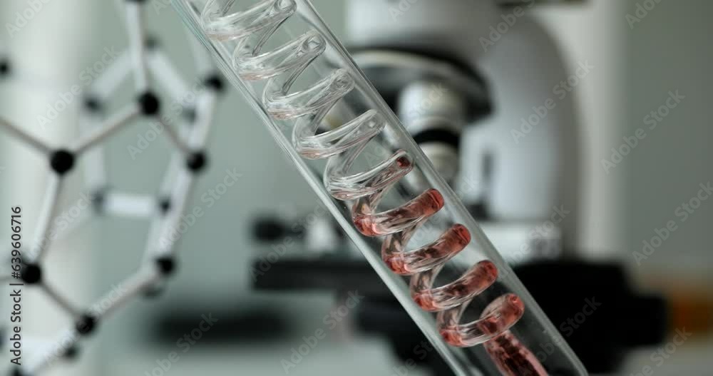 Red transparent liquid flows down spiral plastic pipe in laboratory. Testing toxic liquids Red transparent liquid flows down spiral plastic pipe in laboratory. Testing toxic liquids