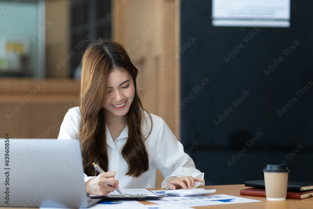 Attractive Asian businesswoman in the office working with financial documents on the desk. Attractive Asian businesswoman in the office working with financial documents on the desk.
