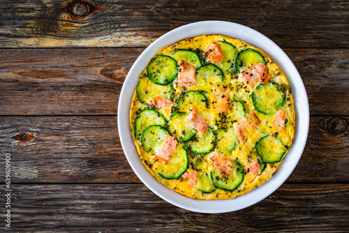 Omelette - scrambled eggs with smoked salmon and zucchini on wooden table