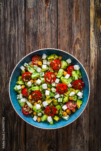 Fresh vegetable salad with feta cheese on wooden table
