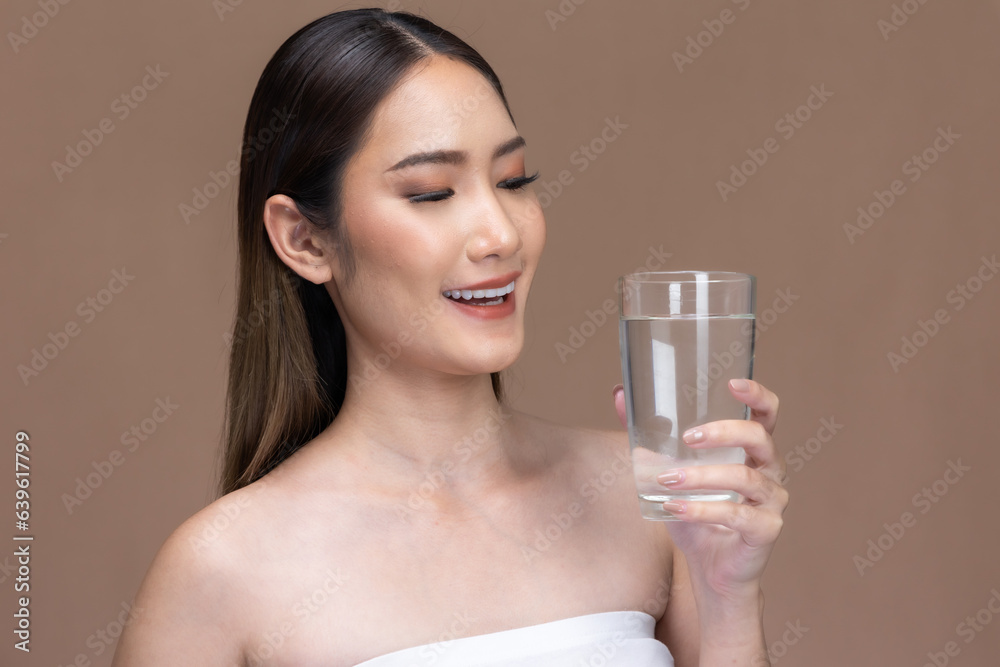 Young Asian woman holding glass of water on beige cream background.Beauty portrait of charm lifestyle healthy and beauty woman. Young Asian woman holding glass of water on beige cream background.Beauty portrait of charm lifestyle healthy and beauty woman.